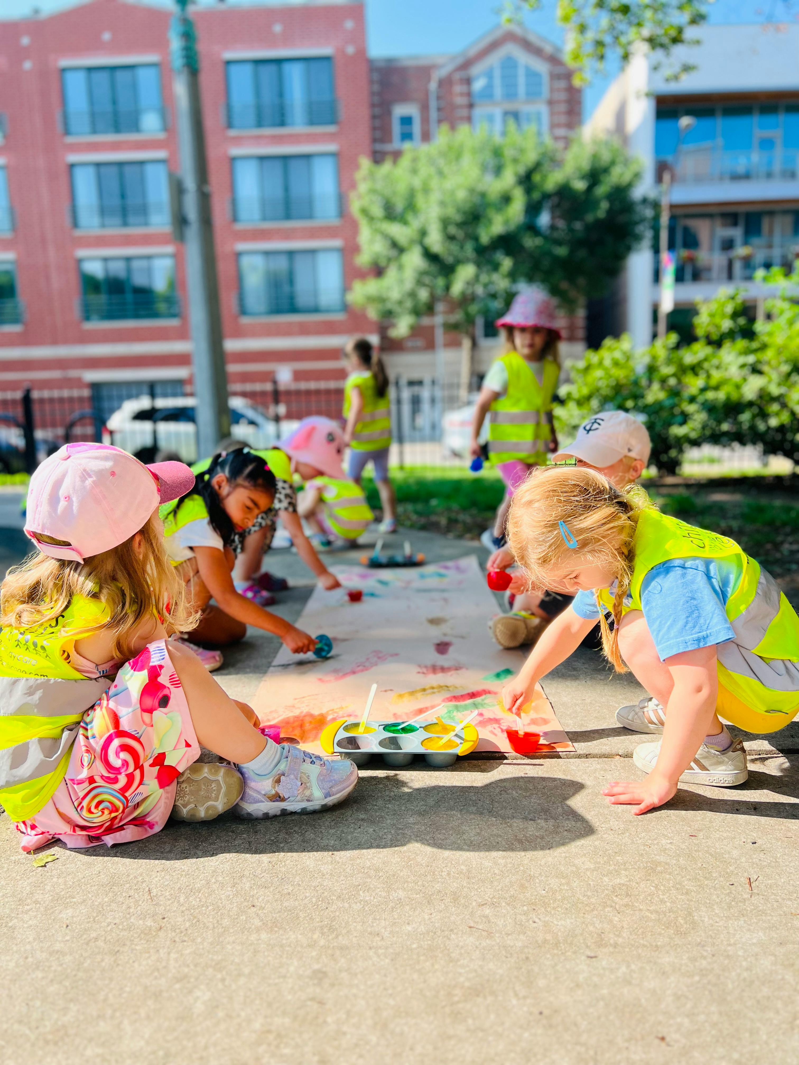 Children painting on paper outdoors