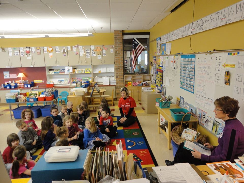 Adults and children sitting on a rug in a classroom