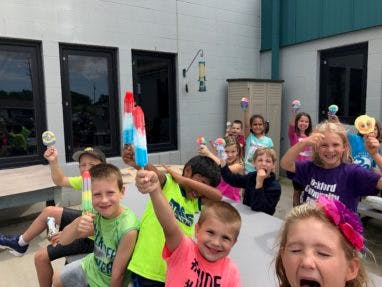 Group of children holding popsicles and candy