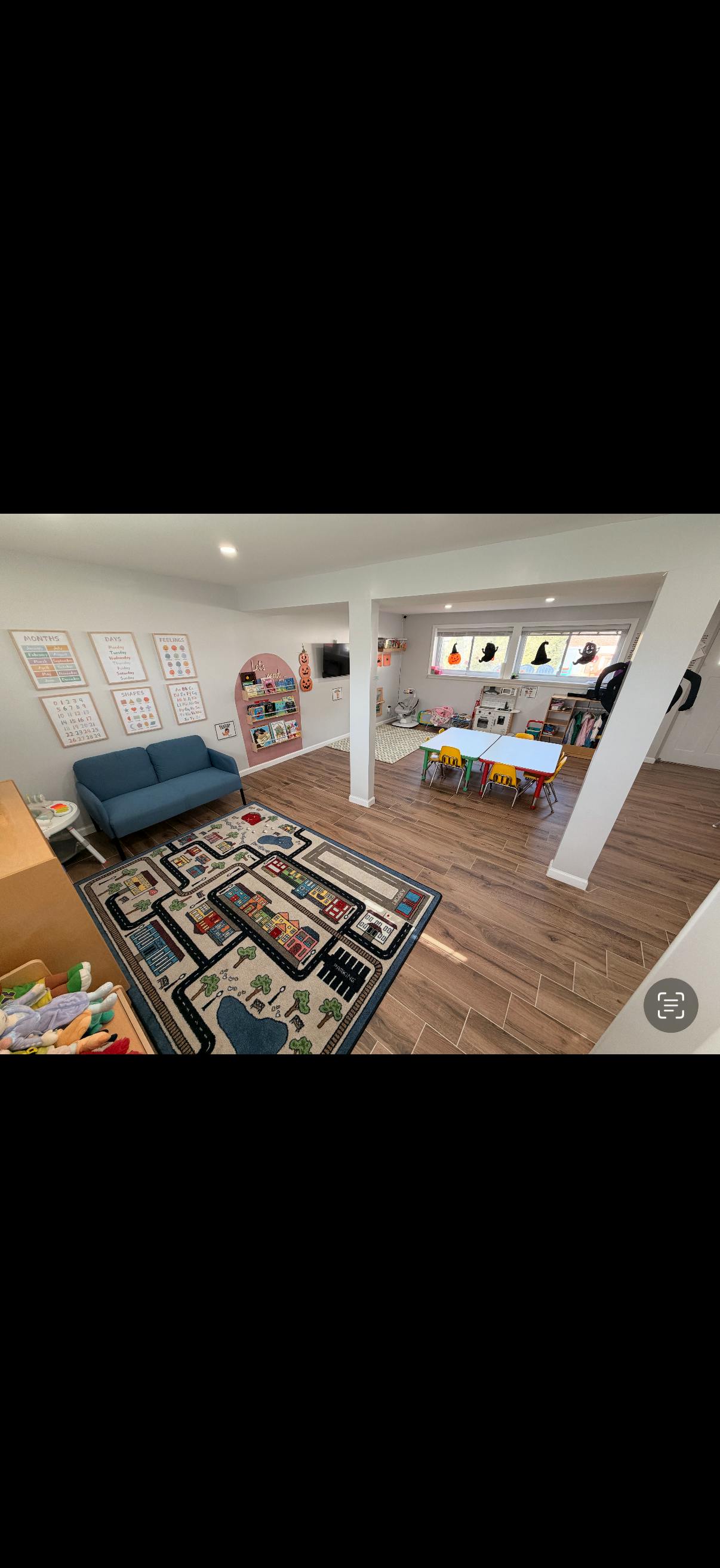 Playroom with a blue sofa, a rug with a road map design, and a table with chairs