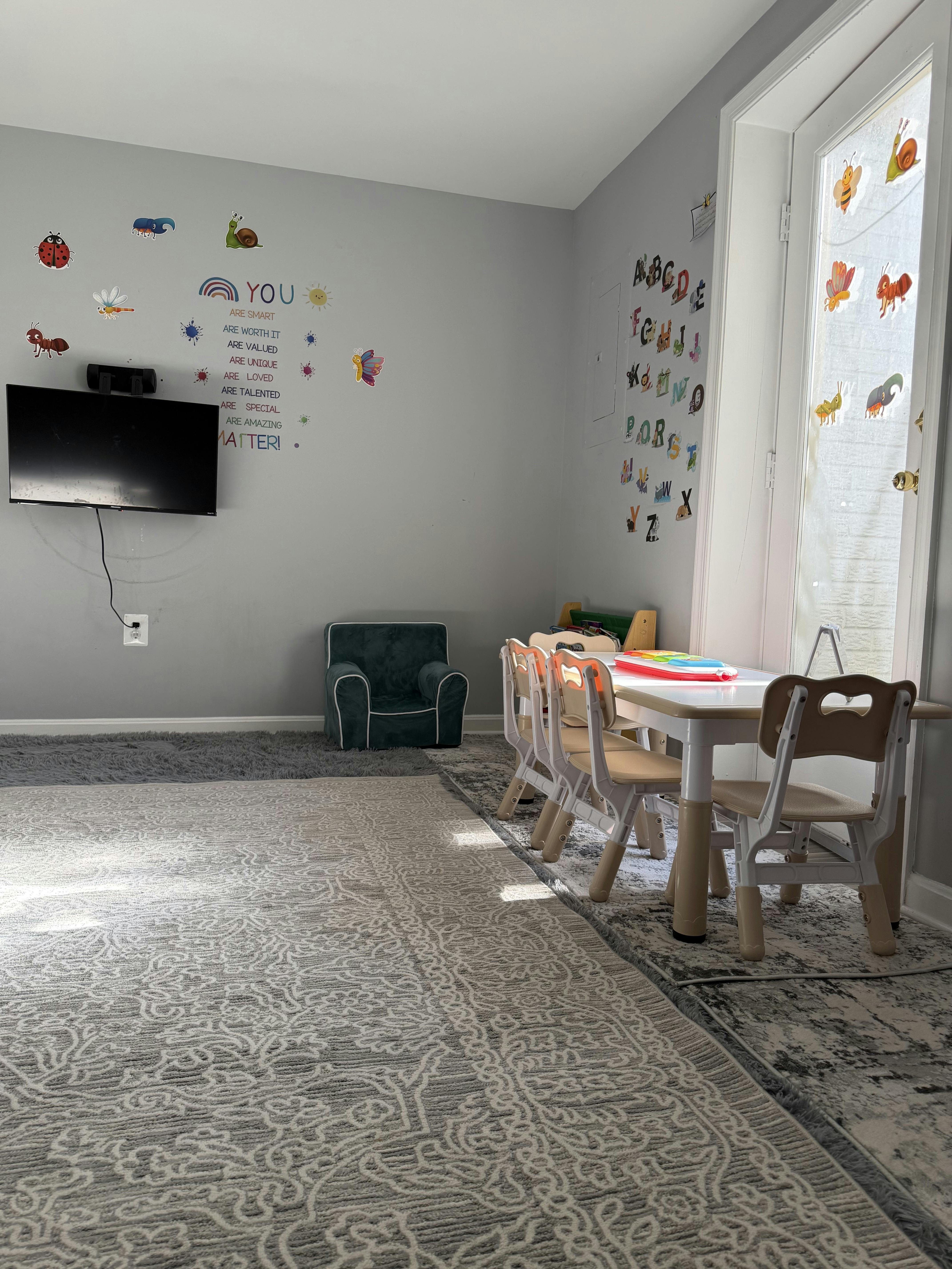 Children's playroom with small table and chairs, television, and wall decals