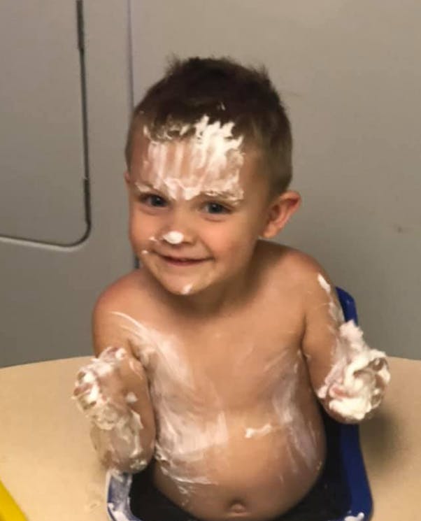 Child covered in white frosting or light-colored cream