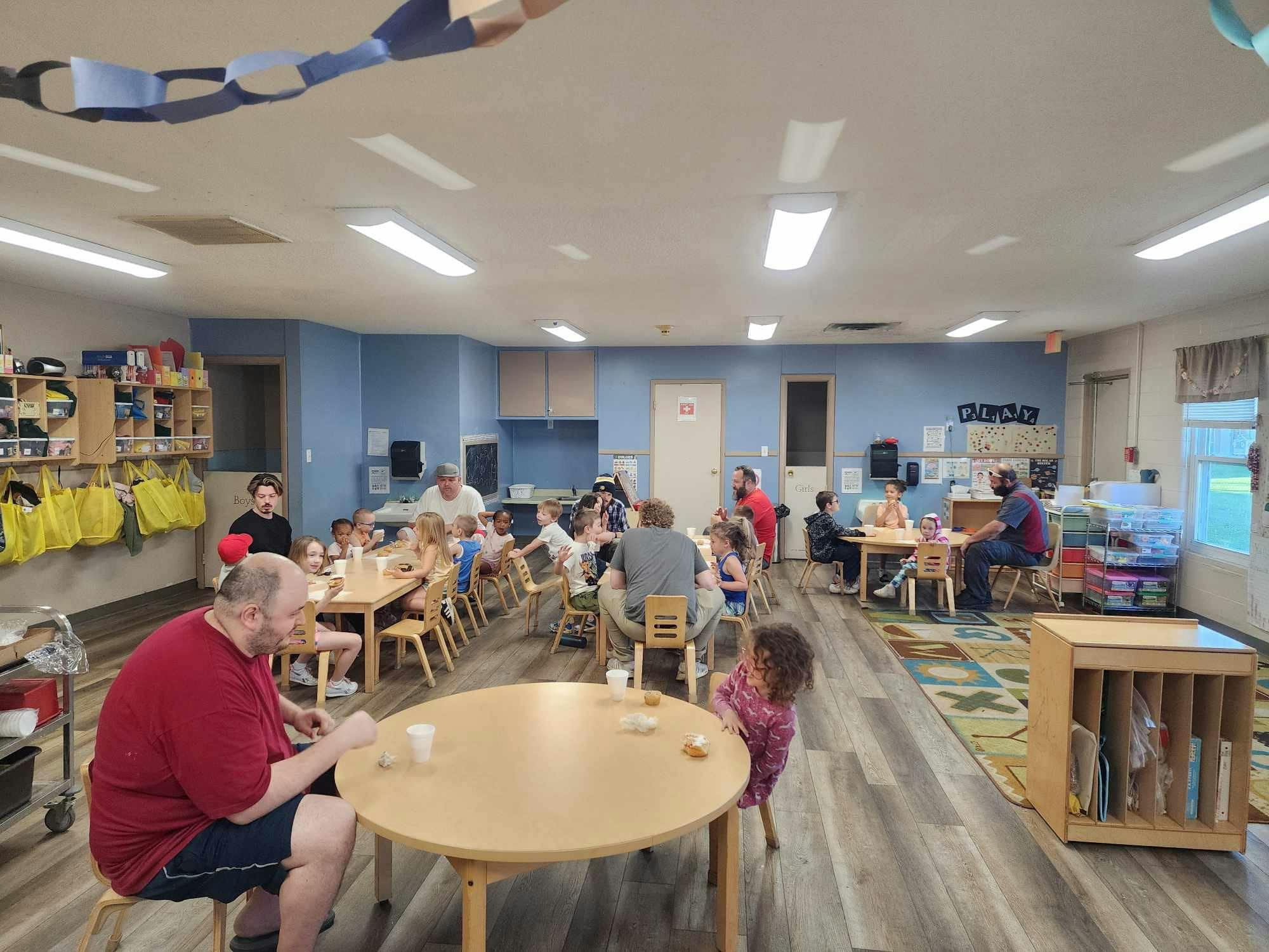People and children sitting at tables in a room