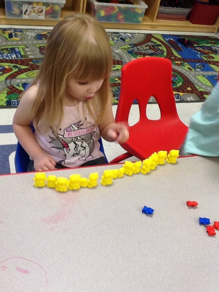 Child playing with yellow counting bears on a table
