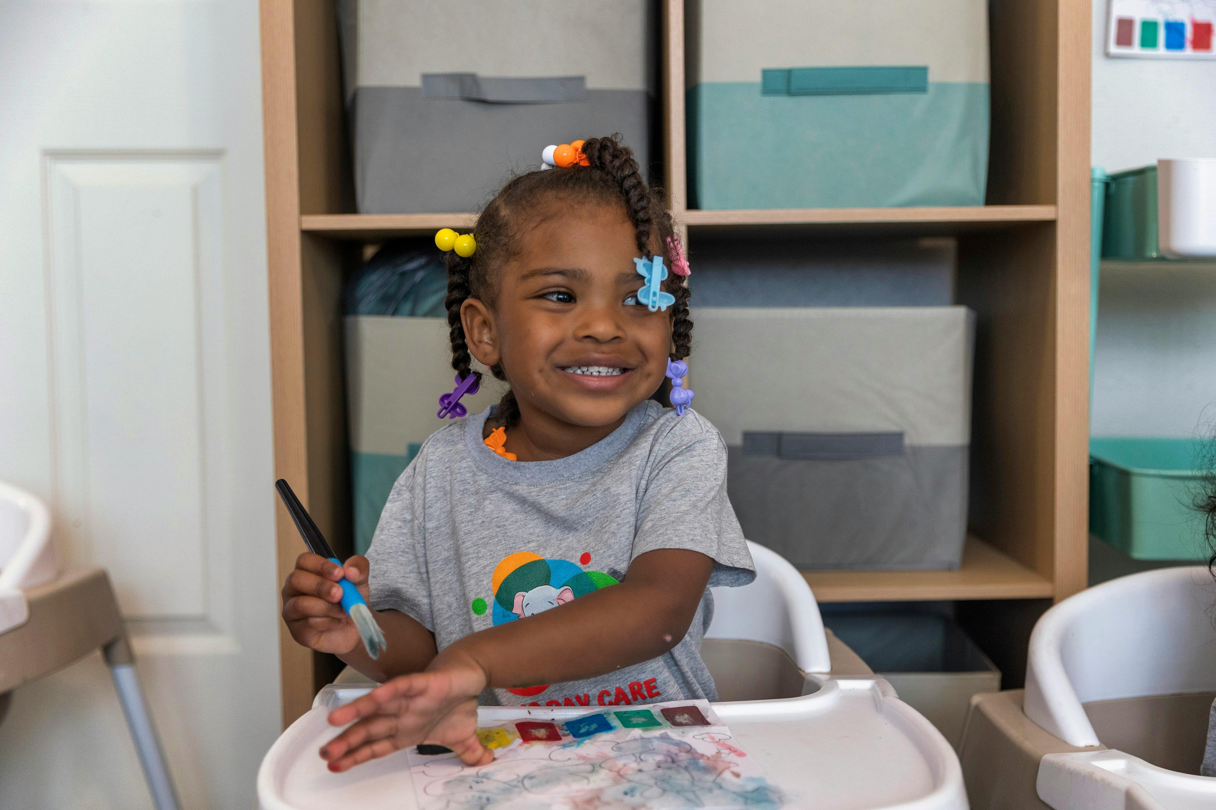 Child in a high chair holding a paintbrush