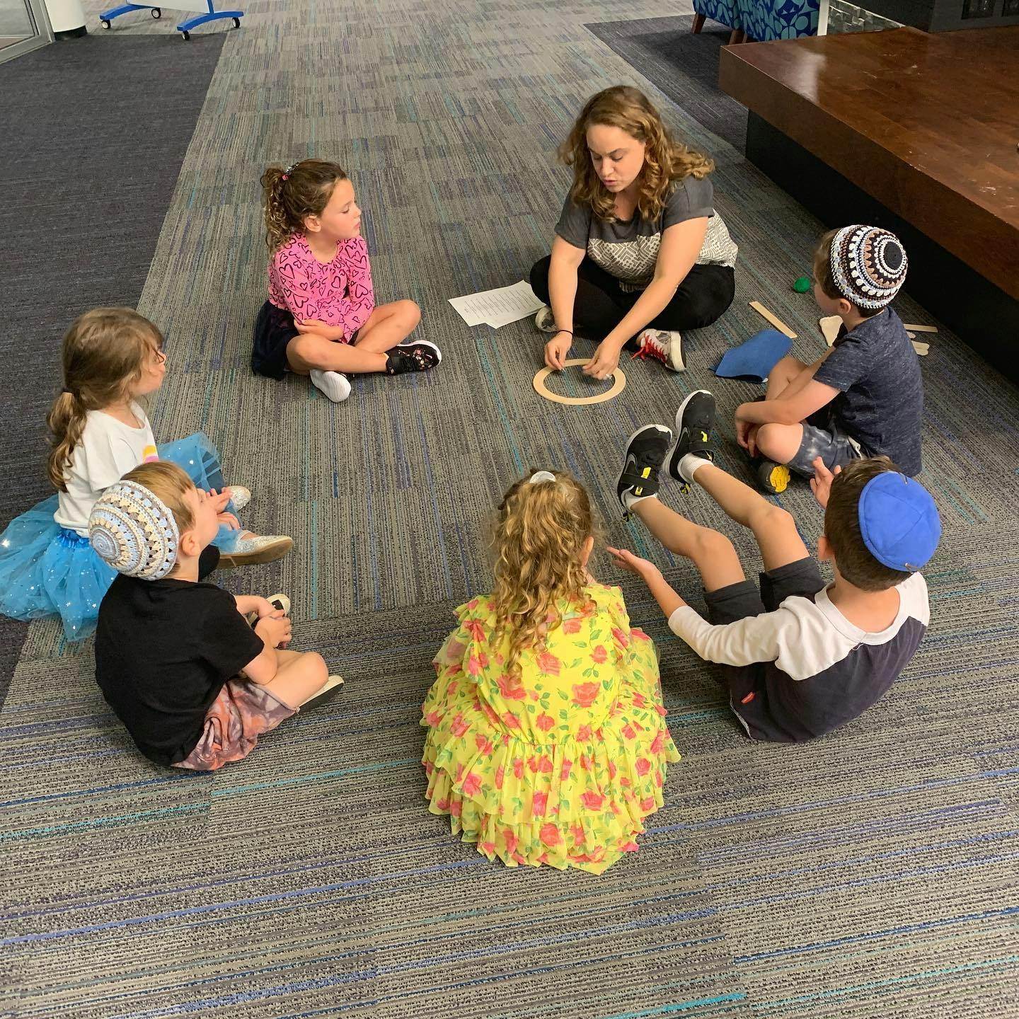 Adult and children sitting on floor in a circle