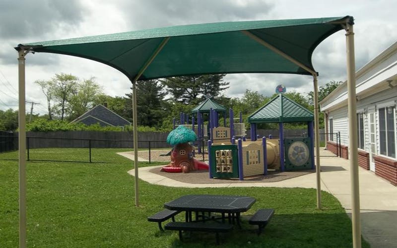 Playground area with a shade structure, picnic table, and play equipment