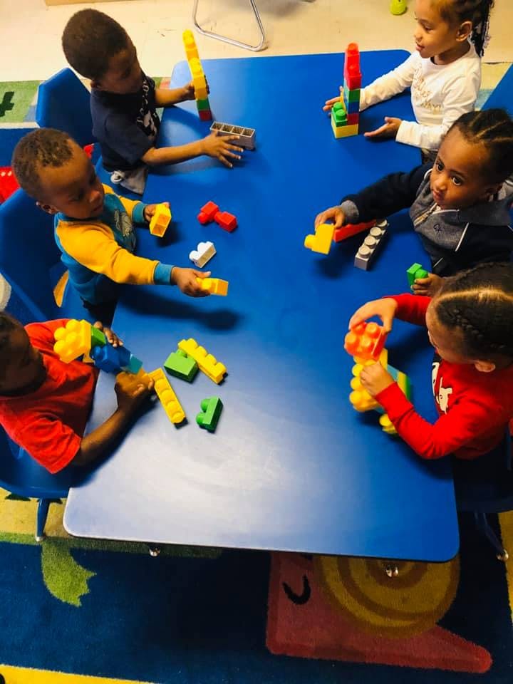 Children playing with colorful building blocks at a blue table