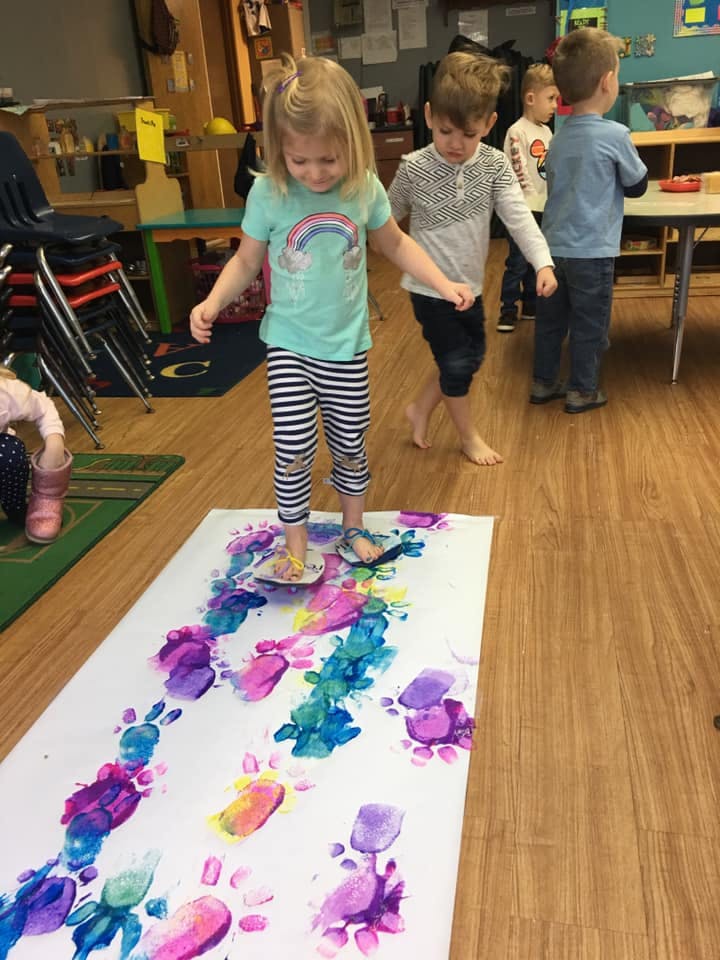Child making colorful footprints on paper
