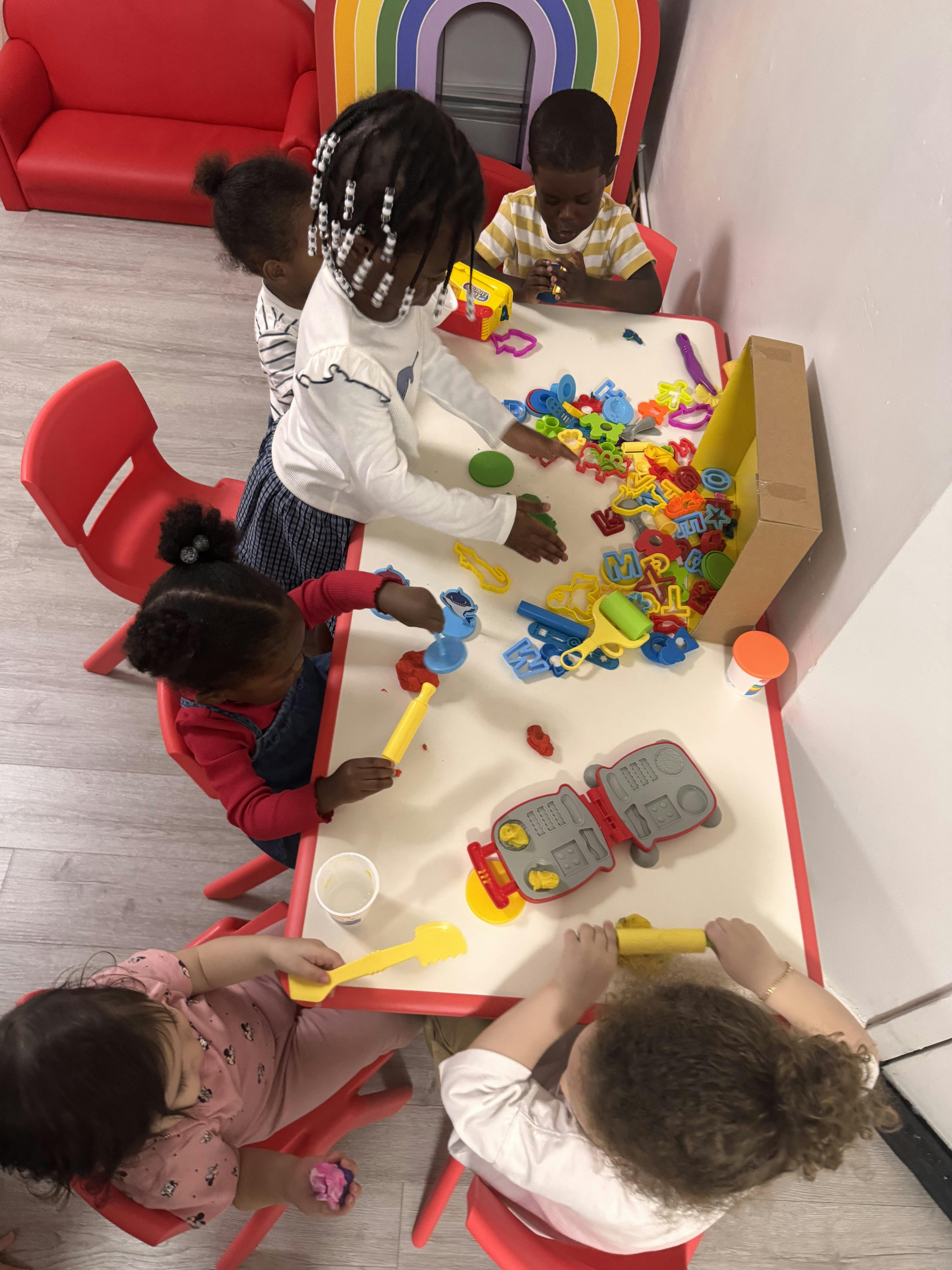 Group of children playing with playdough and toys at a table