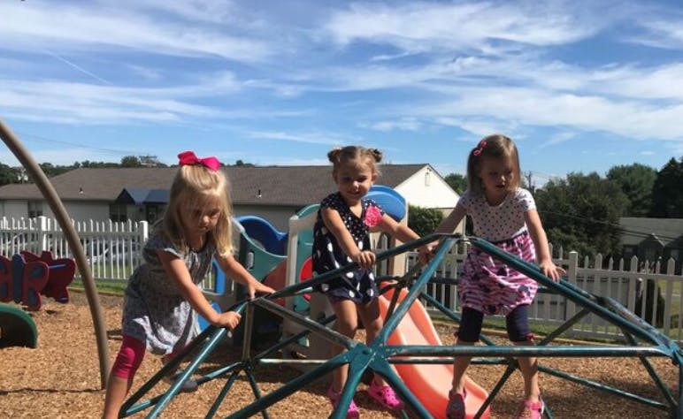 Three children playing on a climbing dome at a playground