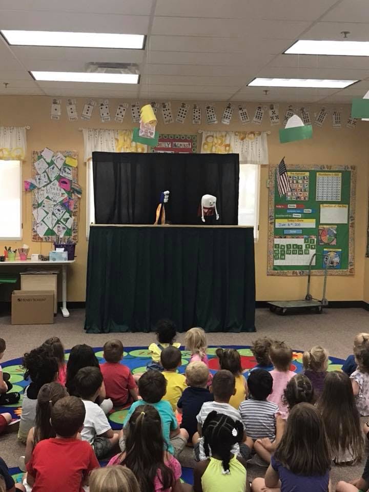 Children watching a puppet show in a classroom