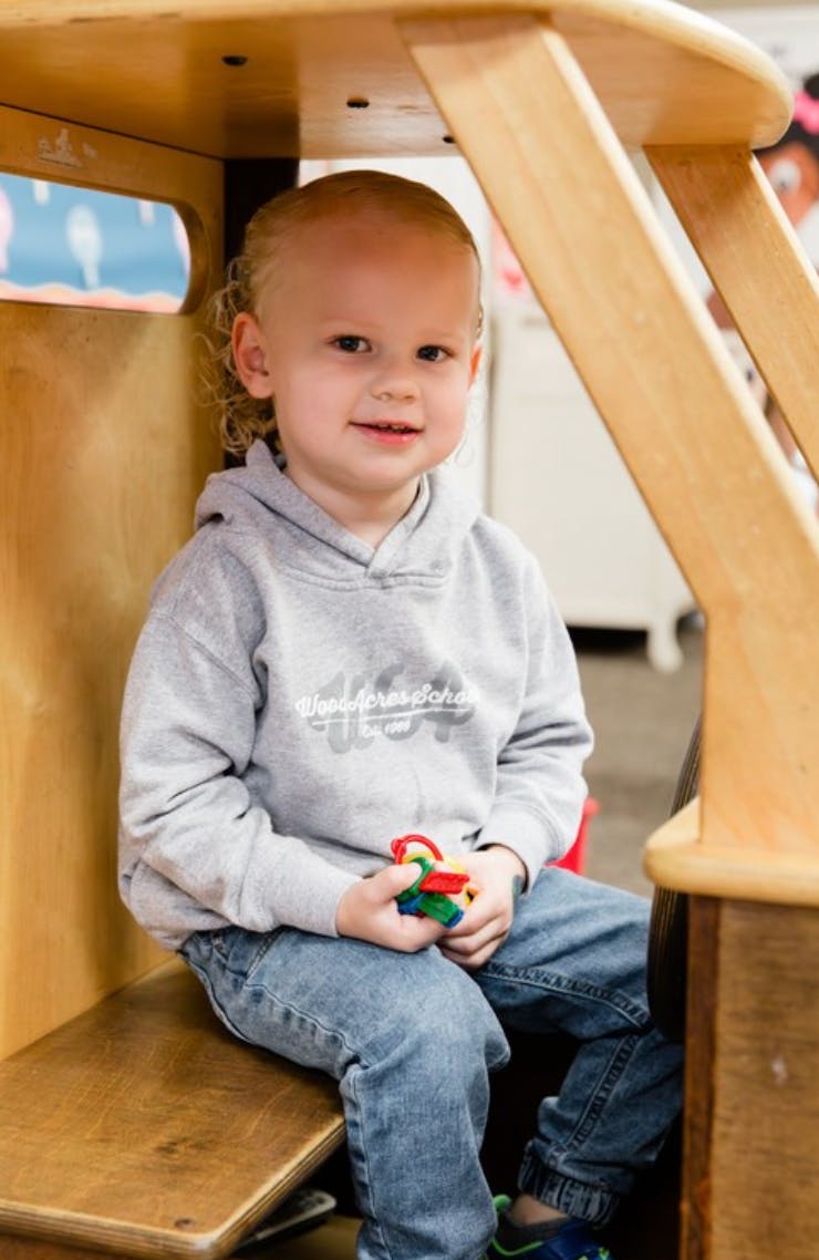 Child smiling while sitting in a wooden structure