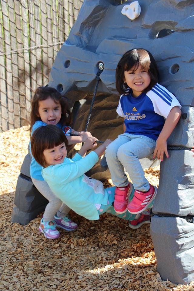 Three children playing on a climbing structure