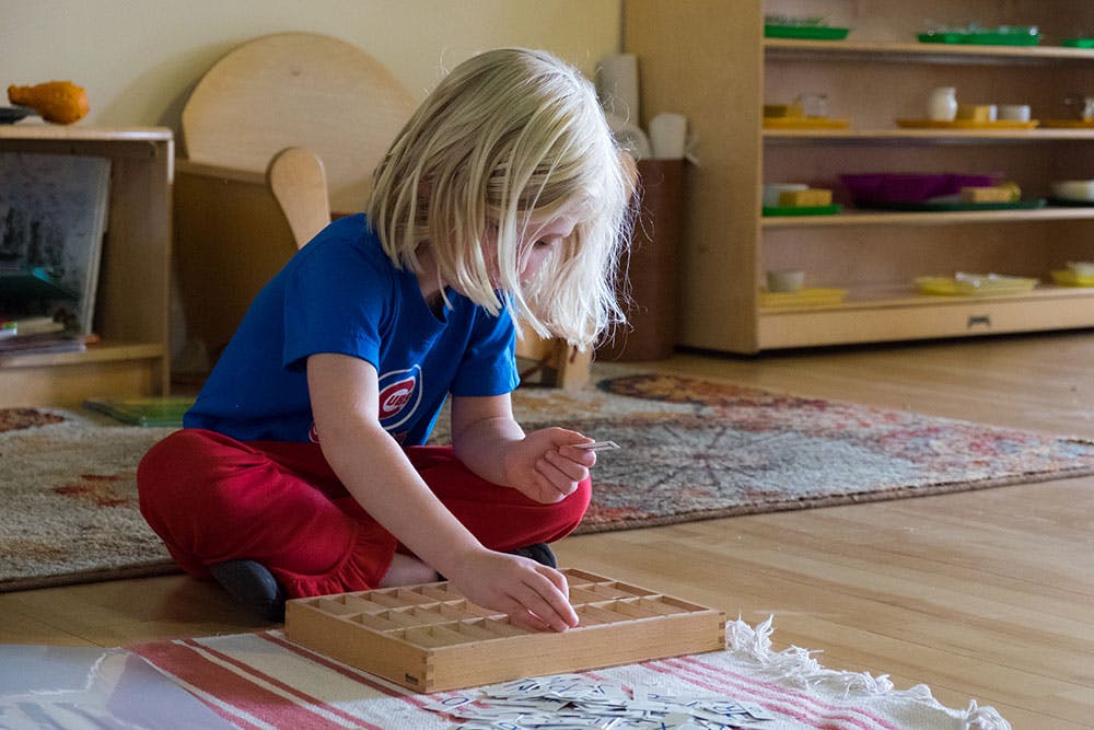 Child playing with a wooden board game on the floor