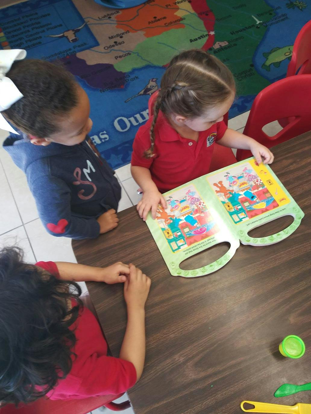 Three children looking at a book on a table