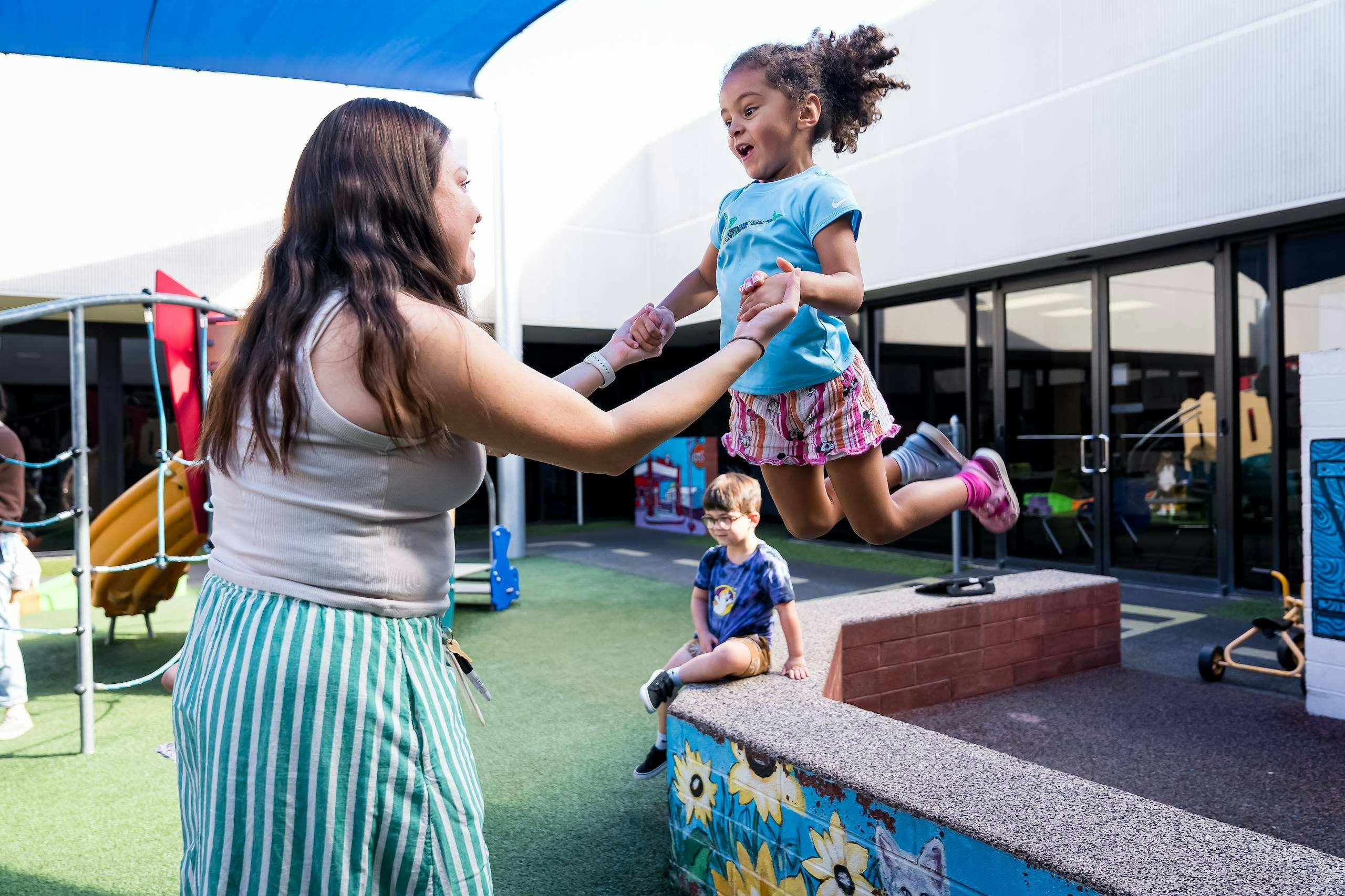 Adult holding a child jumping on a playground