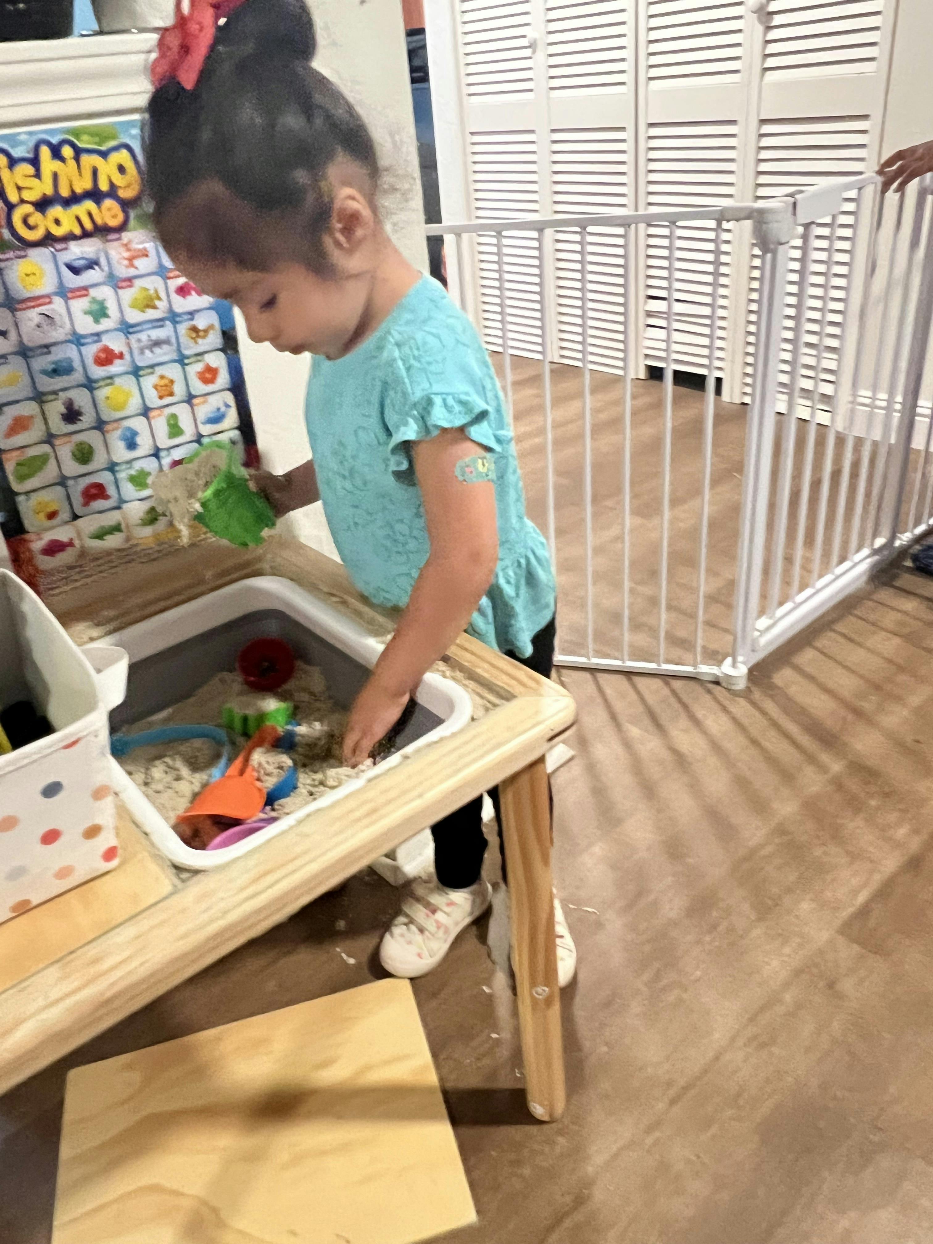 Child playing with sand and toys at a sensory table