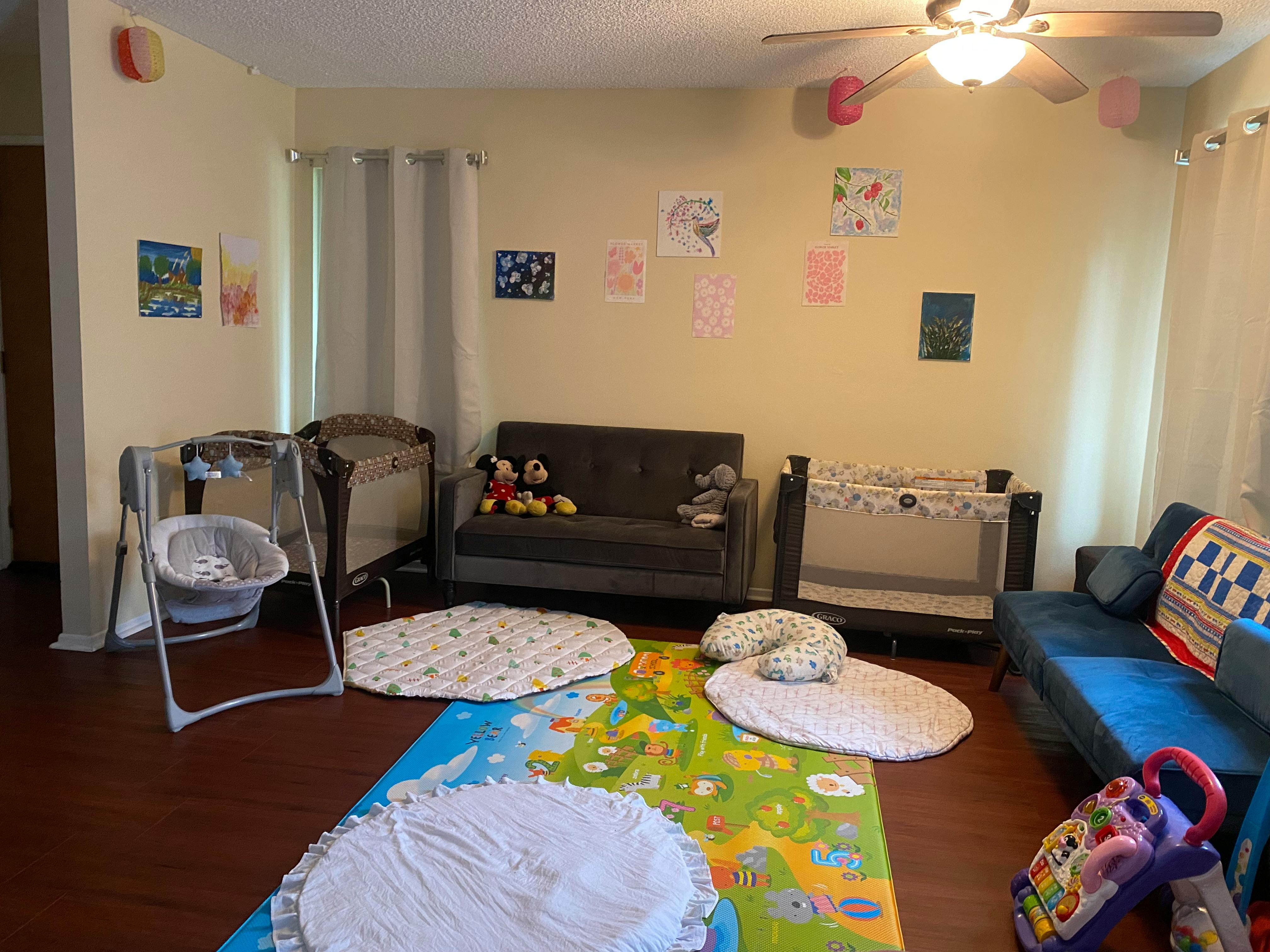 Room with play mats, cribs, and sofas