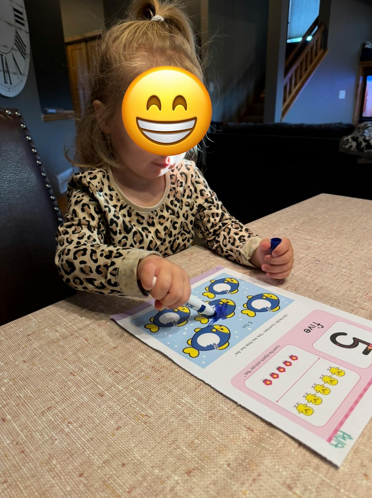 Child using a marker on an educational counting worksheet at a table