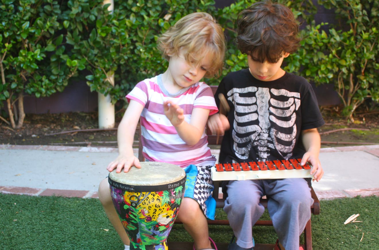 Two children playing musical instruments outdoors