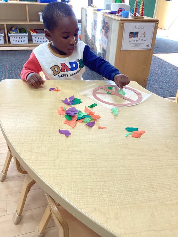 Child crafting with colorful paper cutouts
