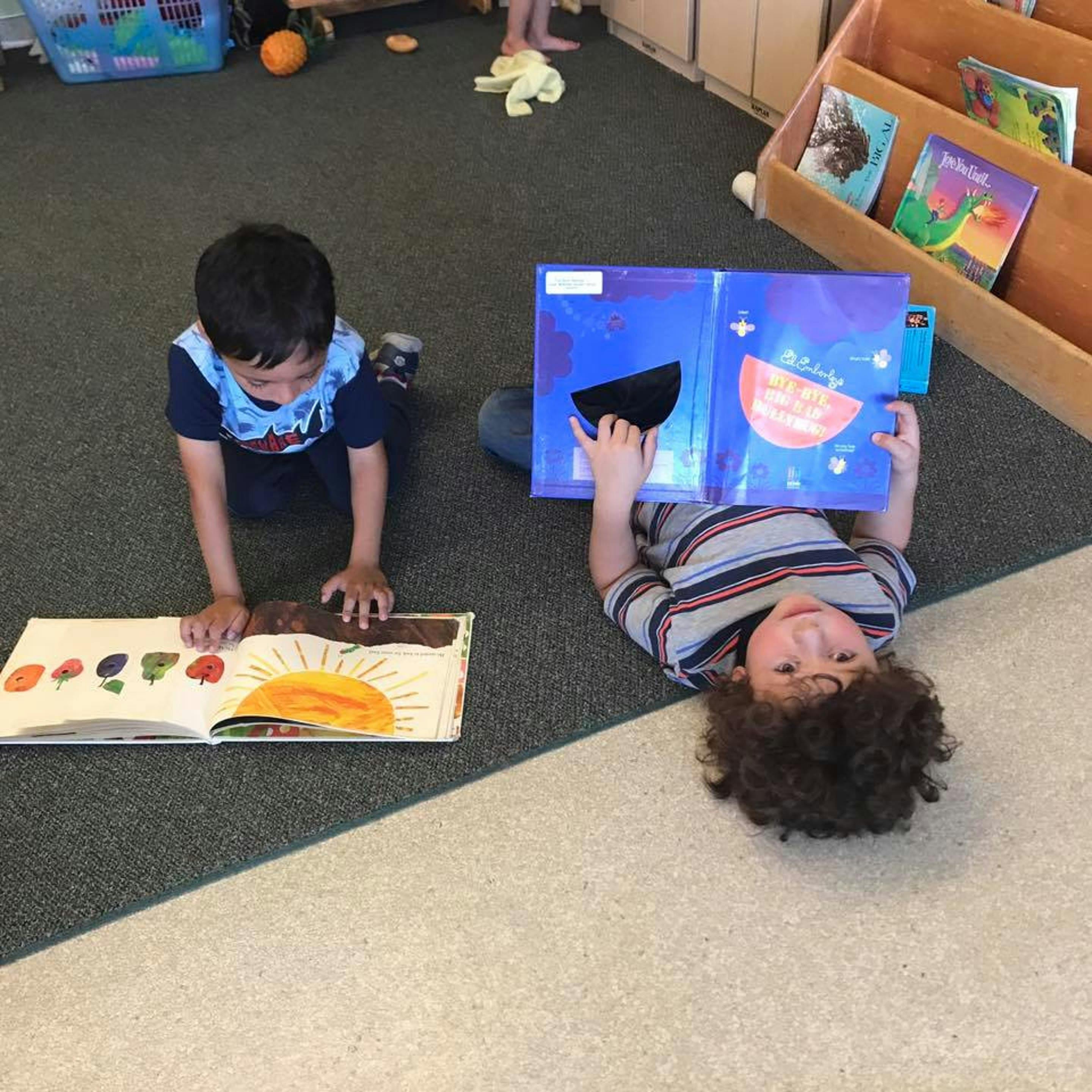 Two children reading books on the floor