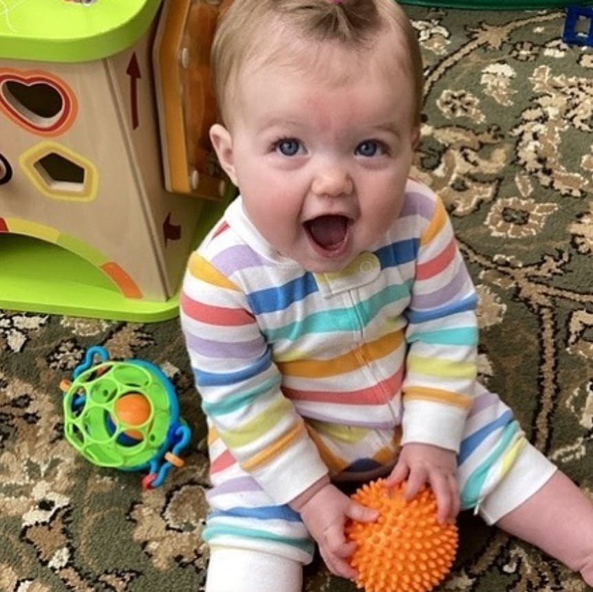 Child in striped pajamas holding an orange spiky ball