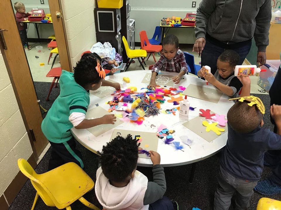 Children doing crafts at a table with an adult supervising