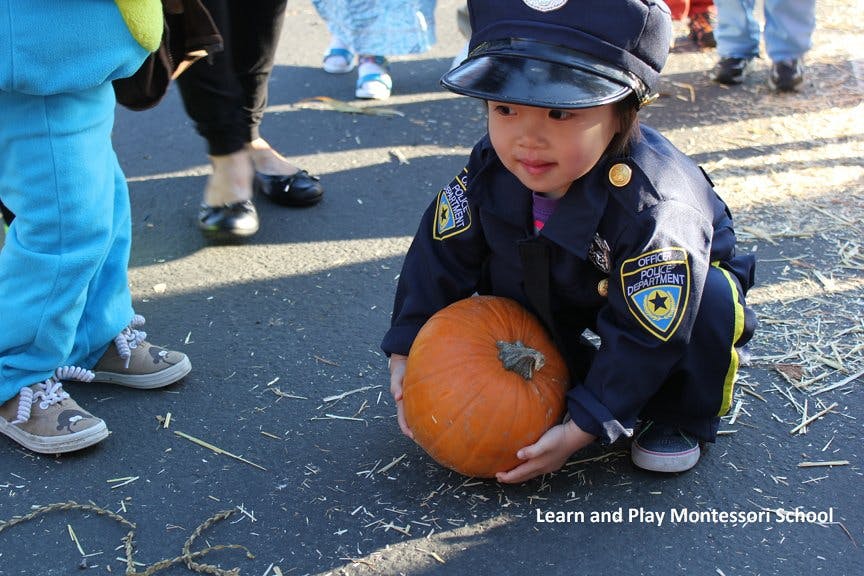 Child in police costume holding a pumpkin