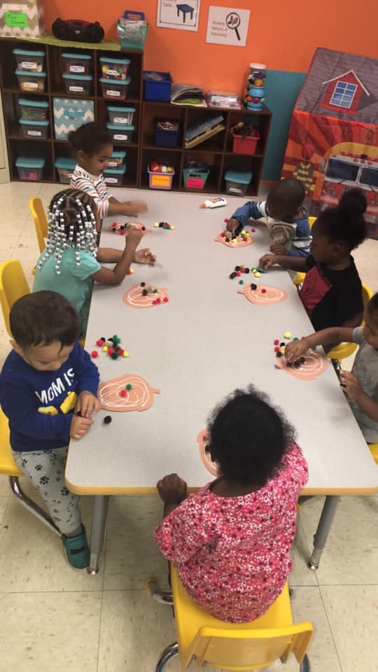 Children at a table doing an art activity with pom-poms