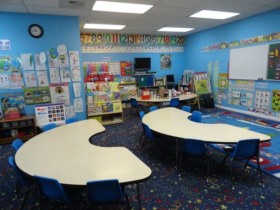 Empty classroom with blue walls, tables, and chairs