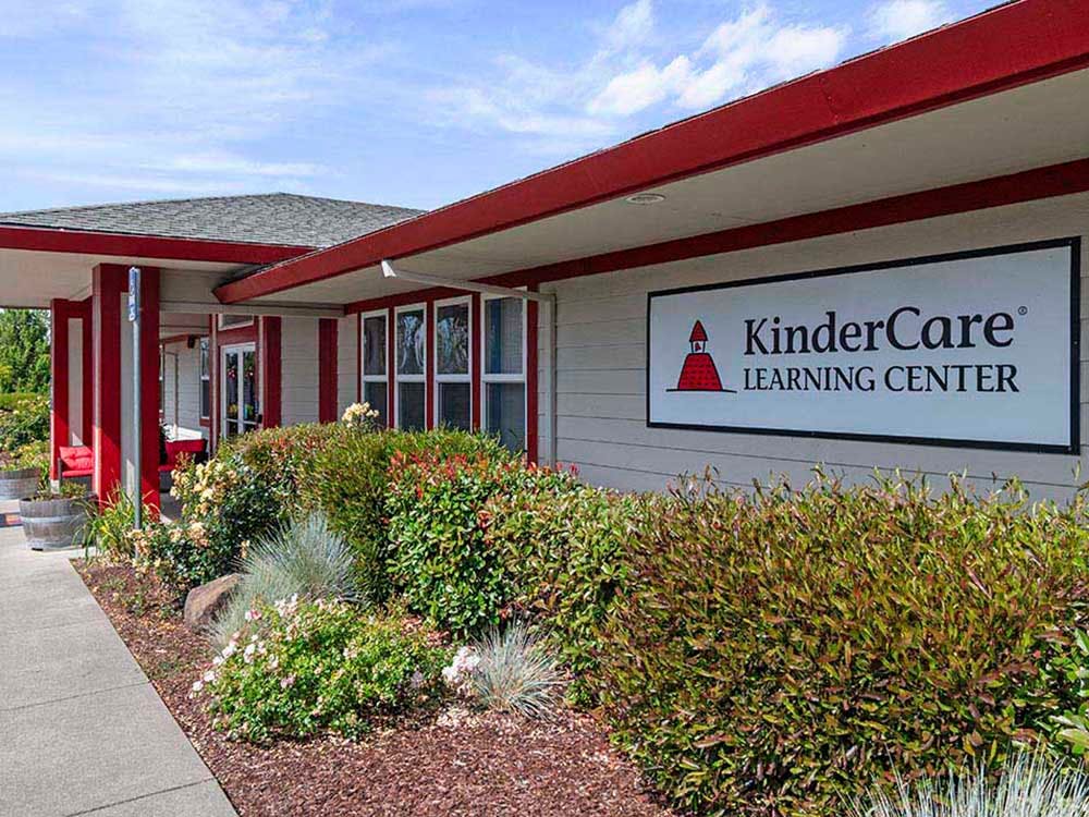 KinderCare Learning Center sign on the side of a building with landscaping