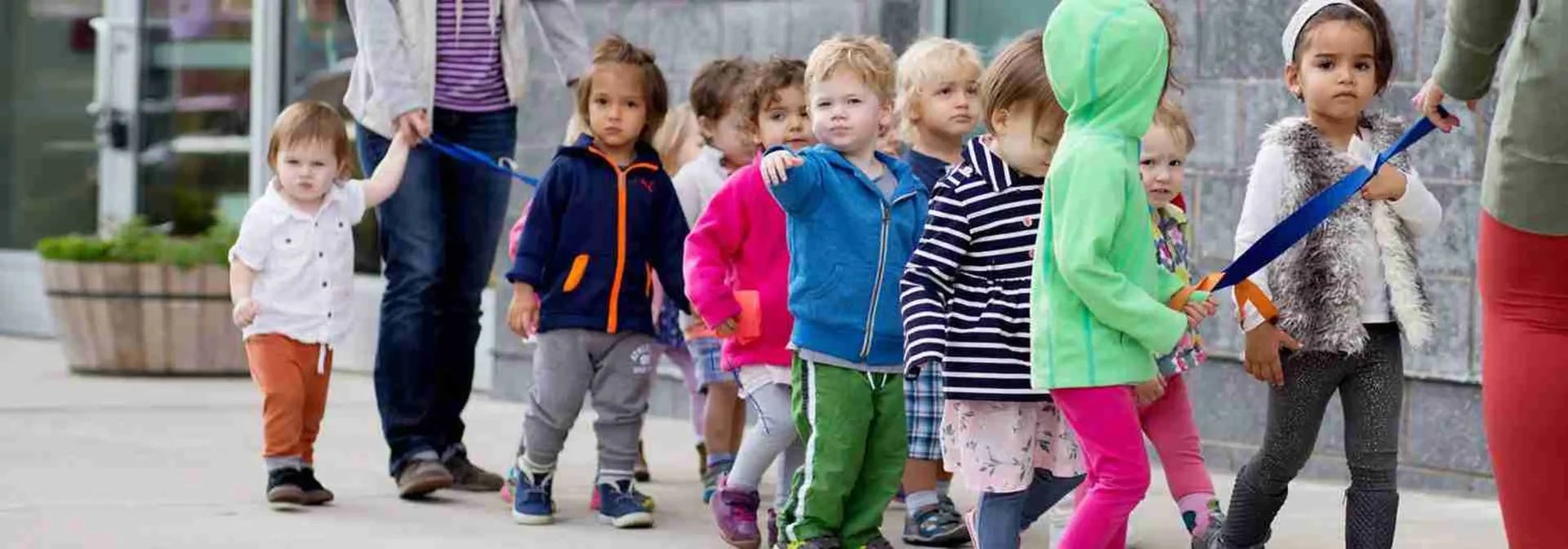 Children in a line holding onto a rope with a person standing at each end