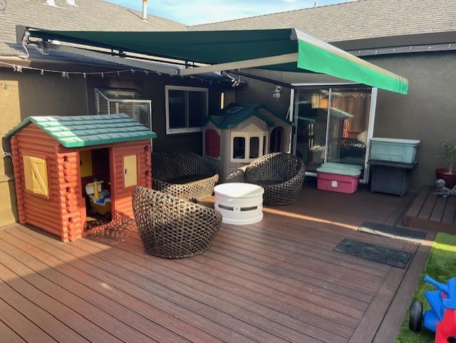 Patio with a green awning, two playhouses, and wicker chairs