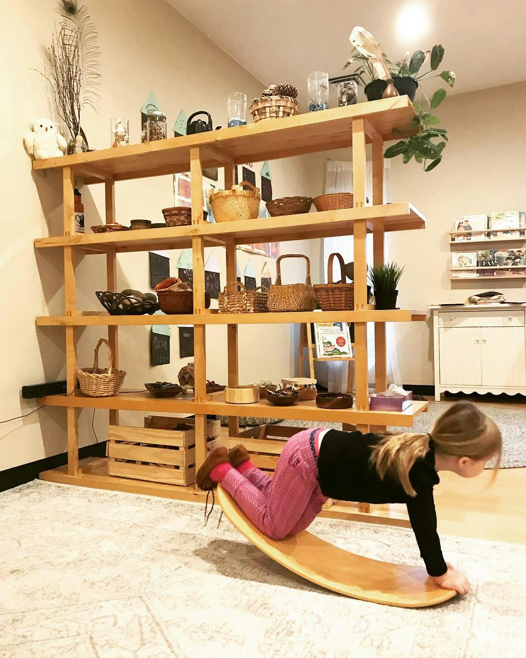 Child on hands and knees on a wooden balance board