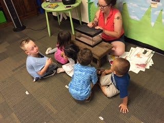 Adult and multiple children gathered around a small tank
