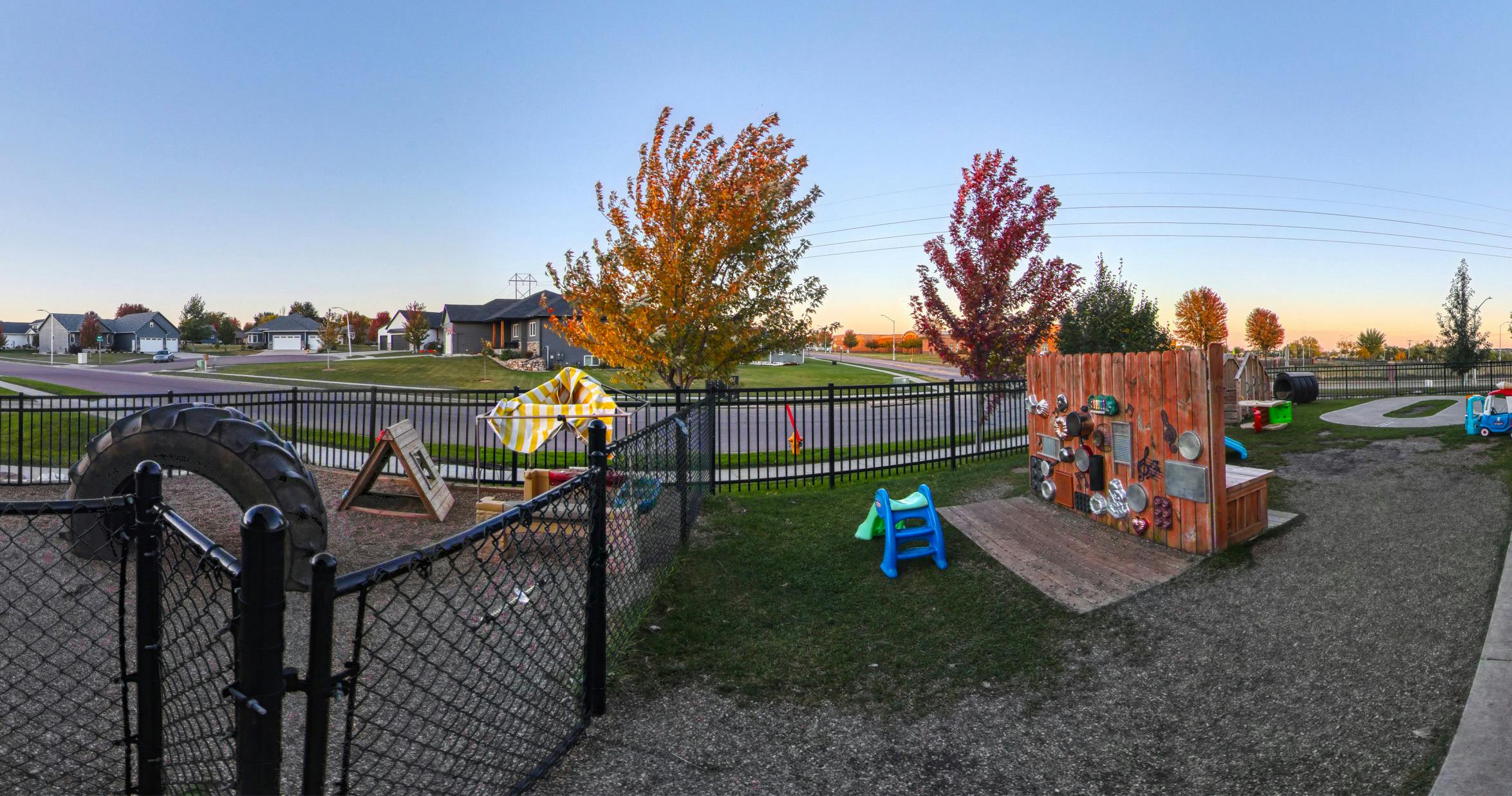 Playground with various equipment and fall foliage, residential area in background