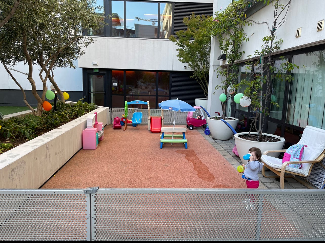 Child playing in an outdoor area with toys and a small slide