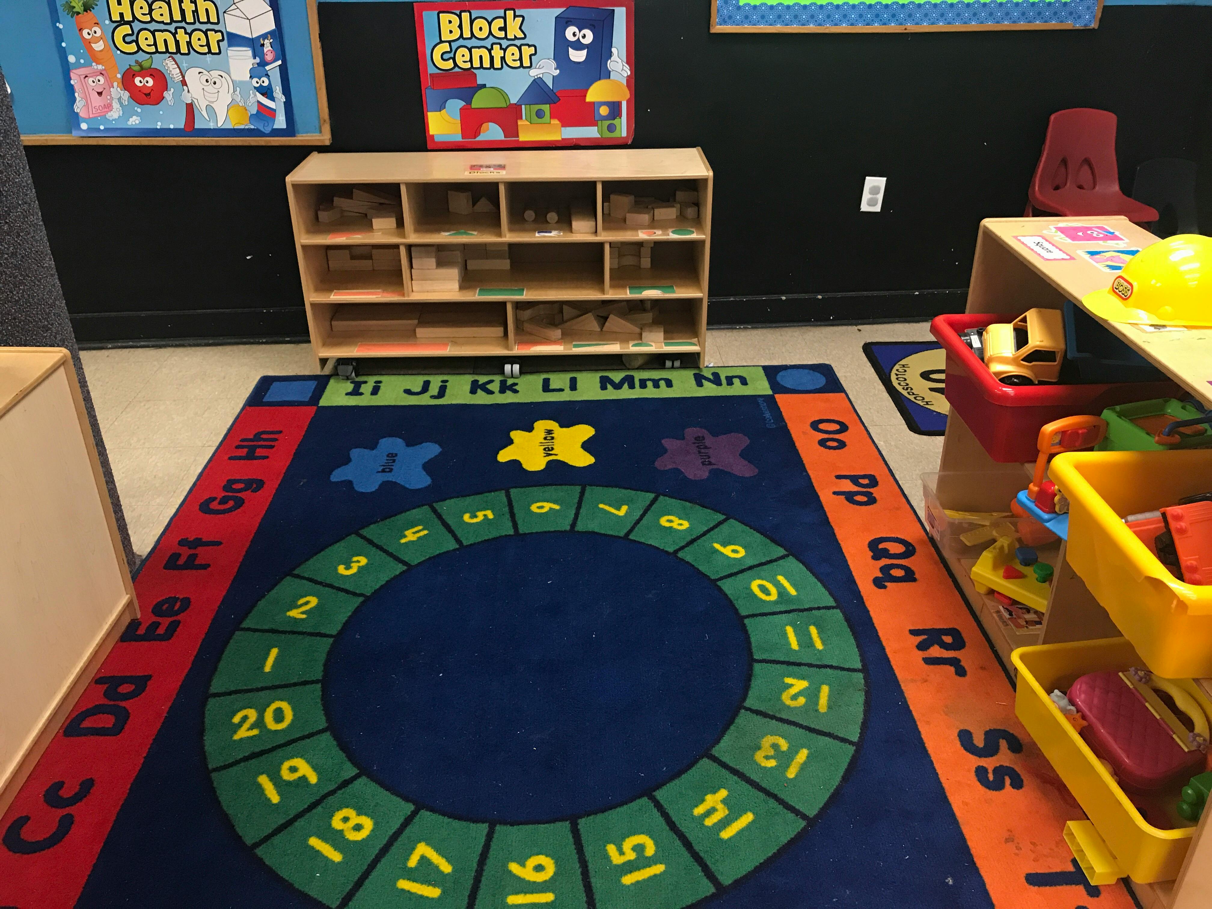 Classroom with a colorful rug featuring numbers and letters