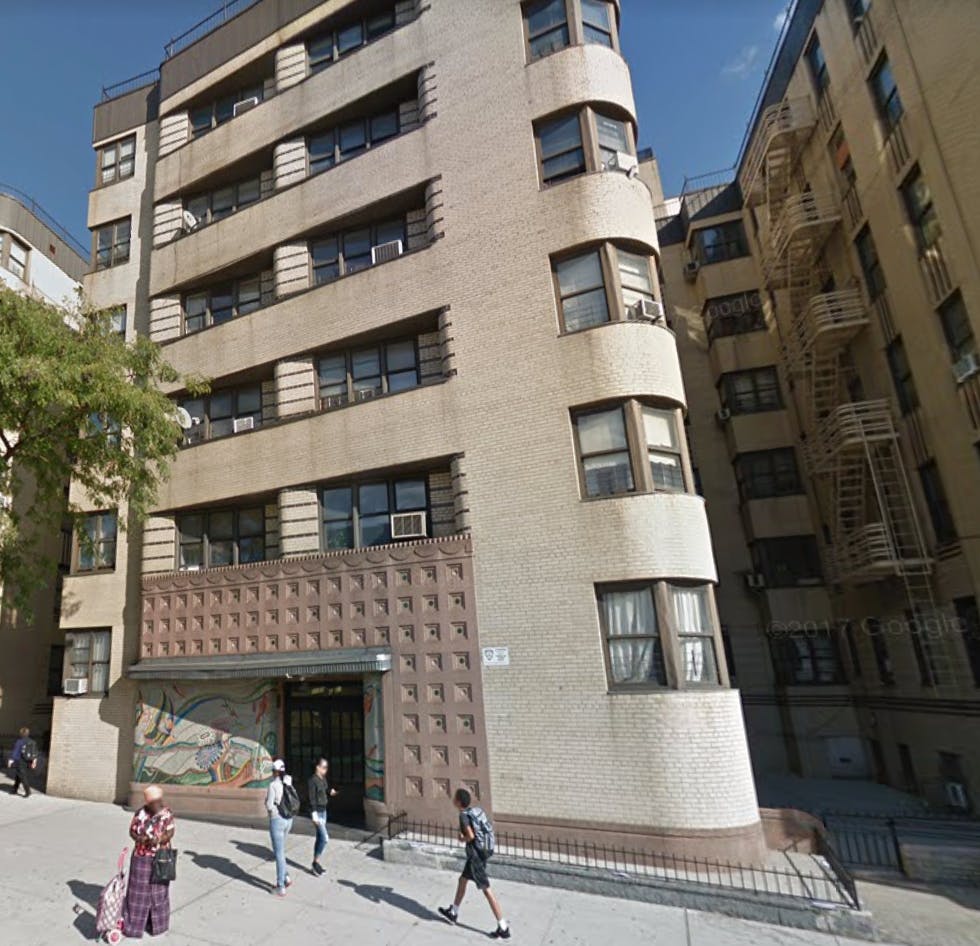 Tall building with multiple windows and people walking on the sidewalk