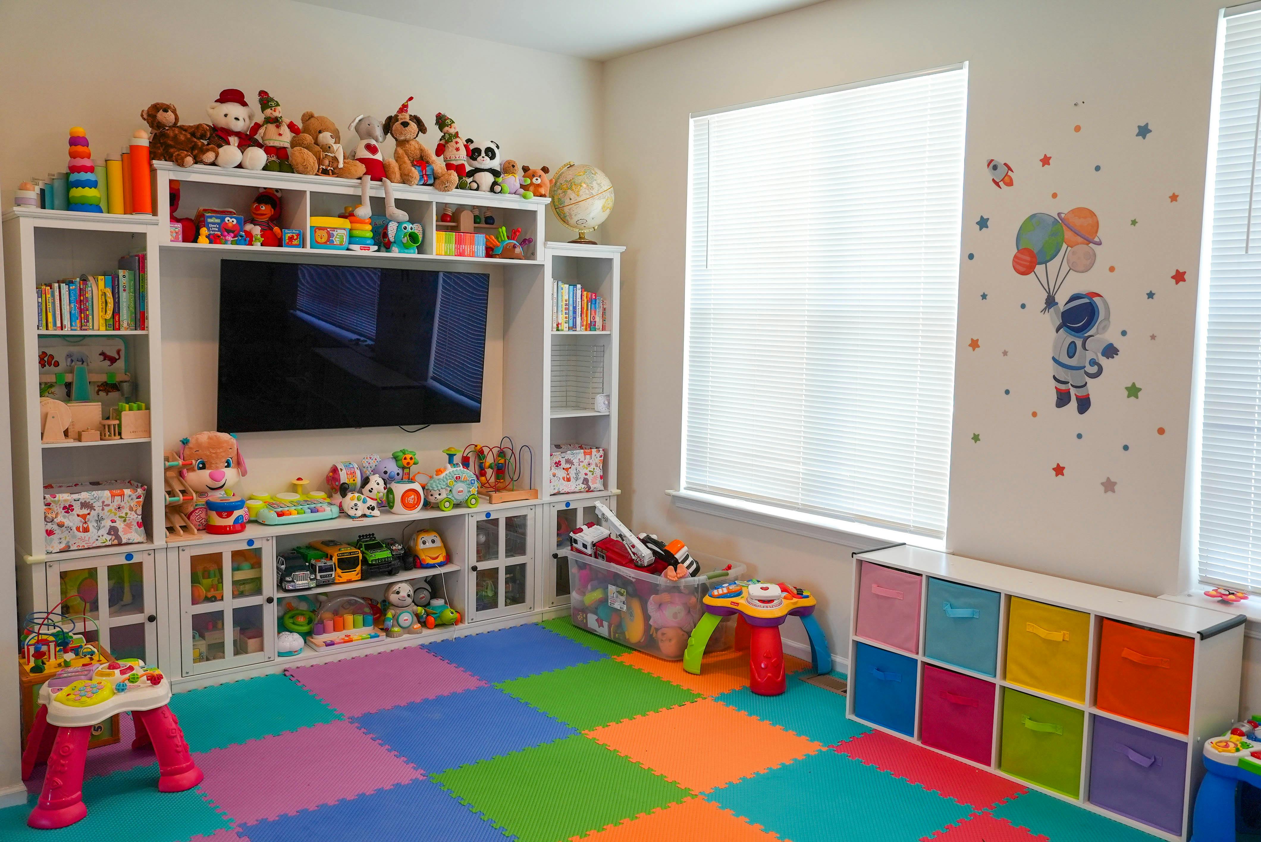 Playroom with a TV, shelves full of toys, and a colorful floor