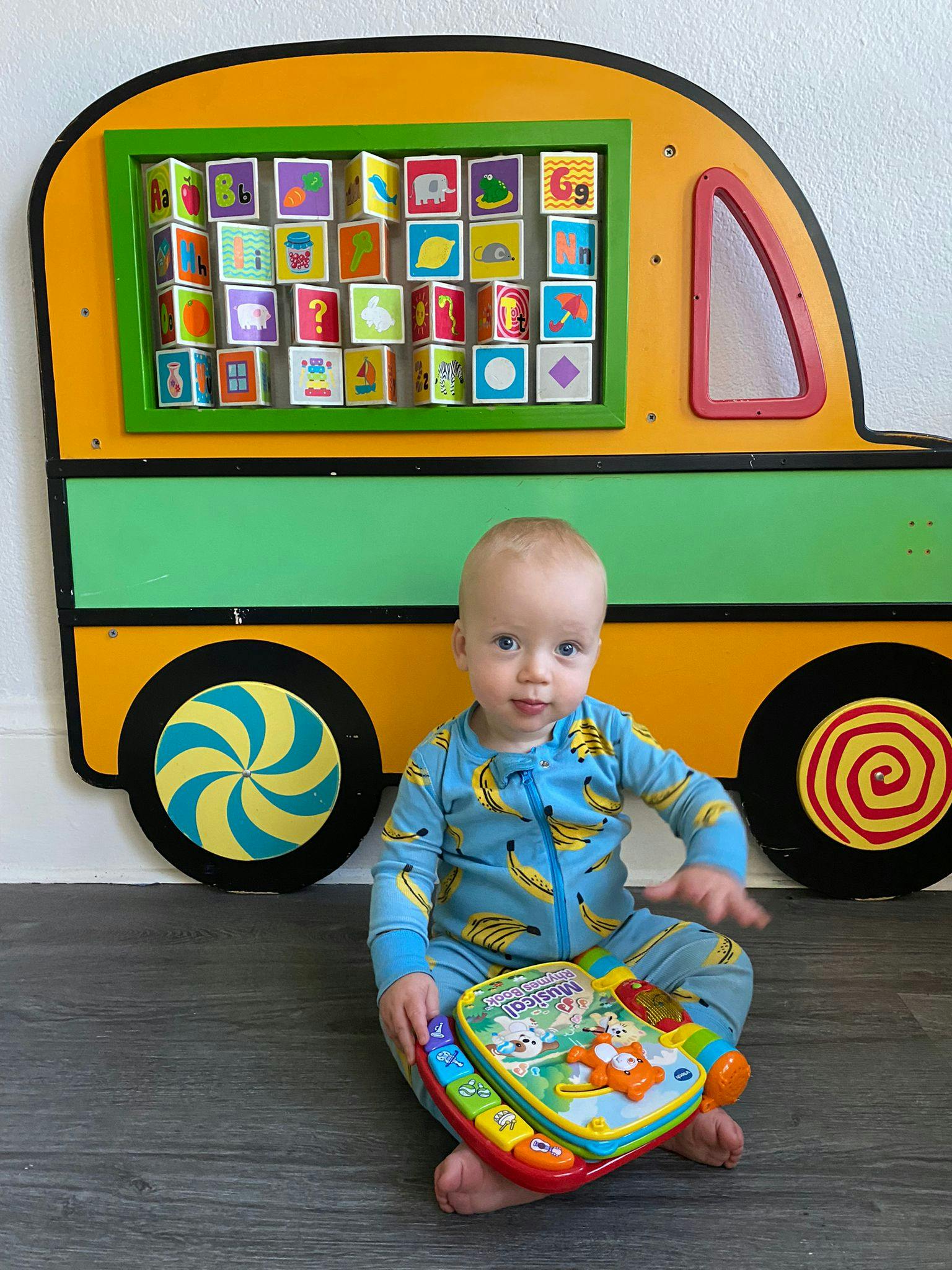 Child sitting on floor in front of a toy bus with alphabet blocks