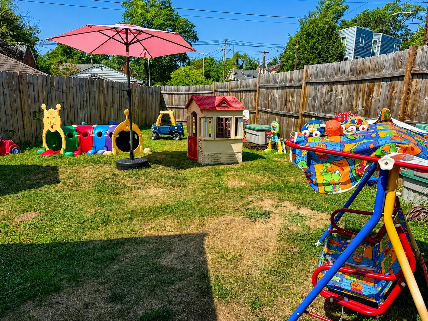 Colorful plastic play equipment for children in a fenced backyard