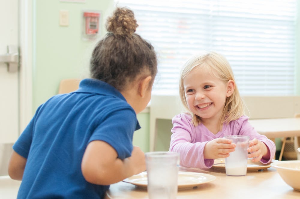 Two children sitting at a table with drinks