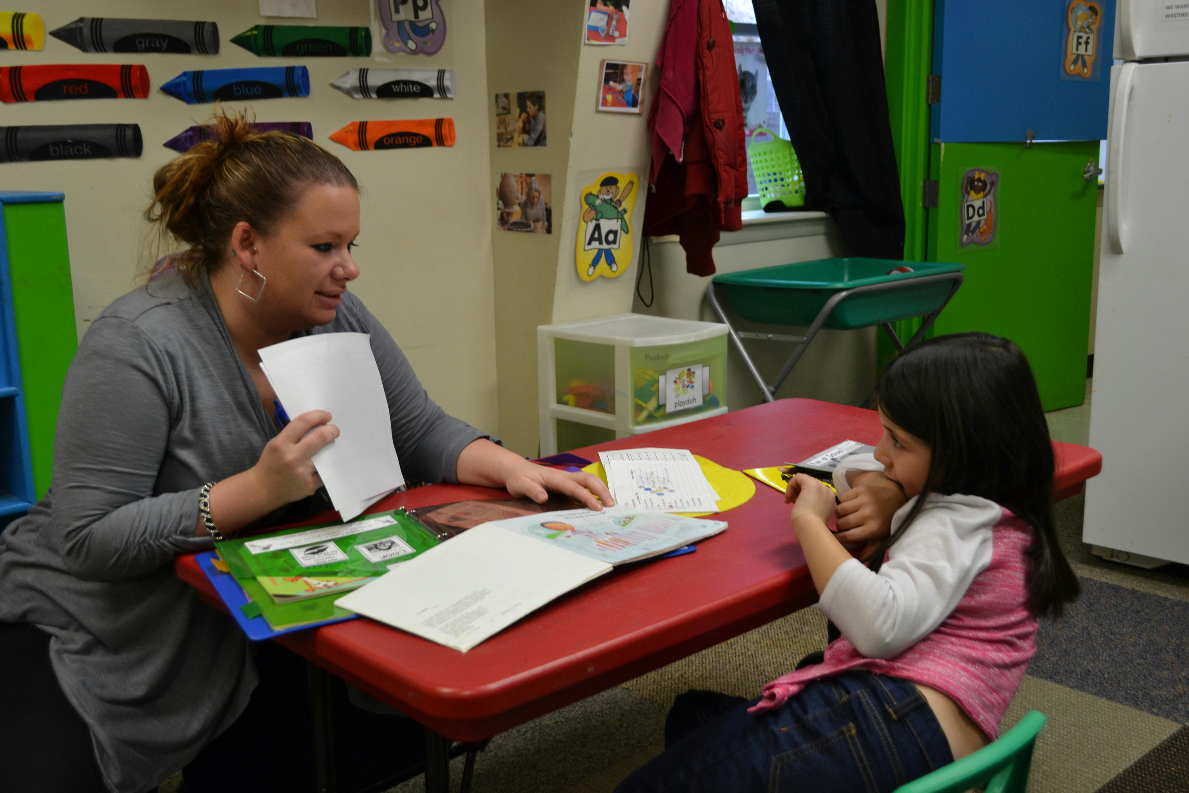 Adult and child sitting at a table with books and papers