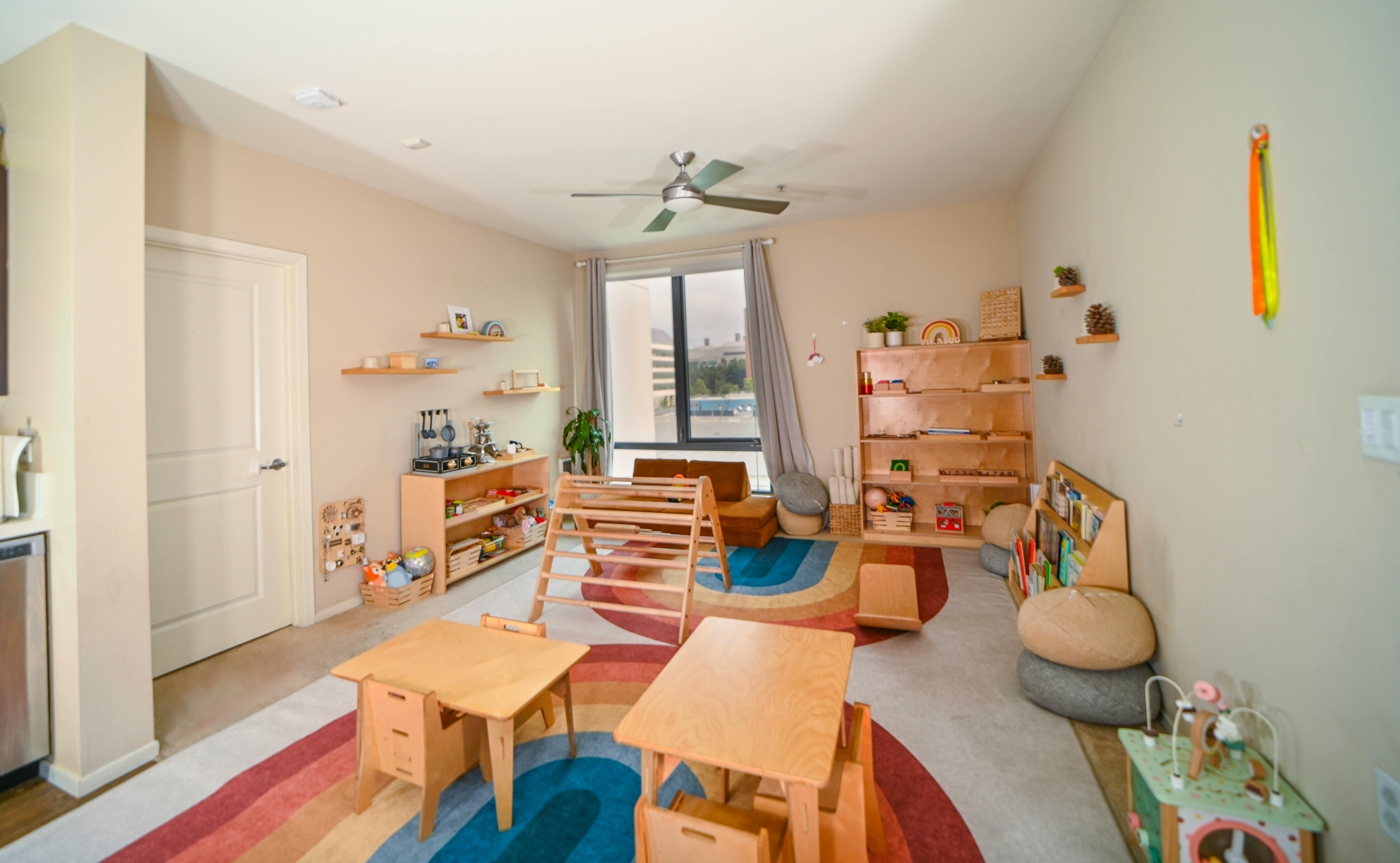 Children's play area with small tables and chairs on a rainbow rug