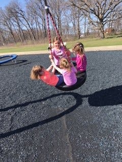 Three children on a tire swing