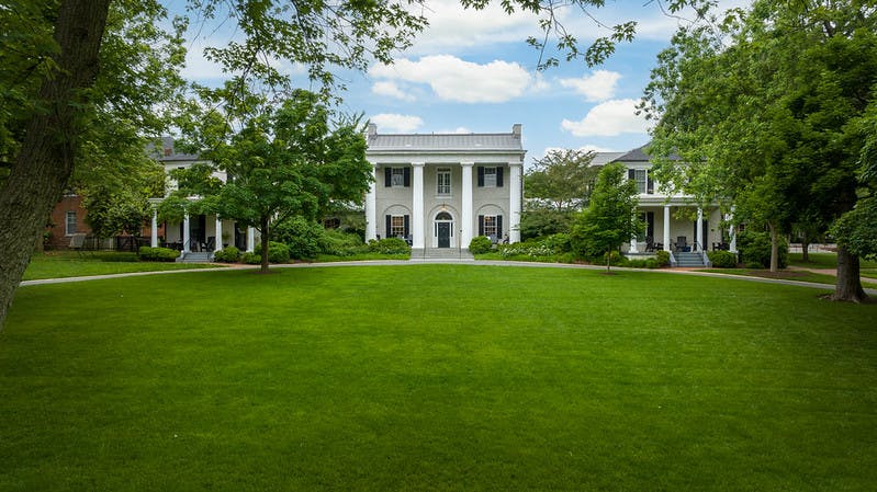 large white building with columns and a green lawn in front