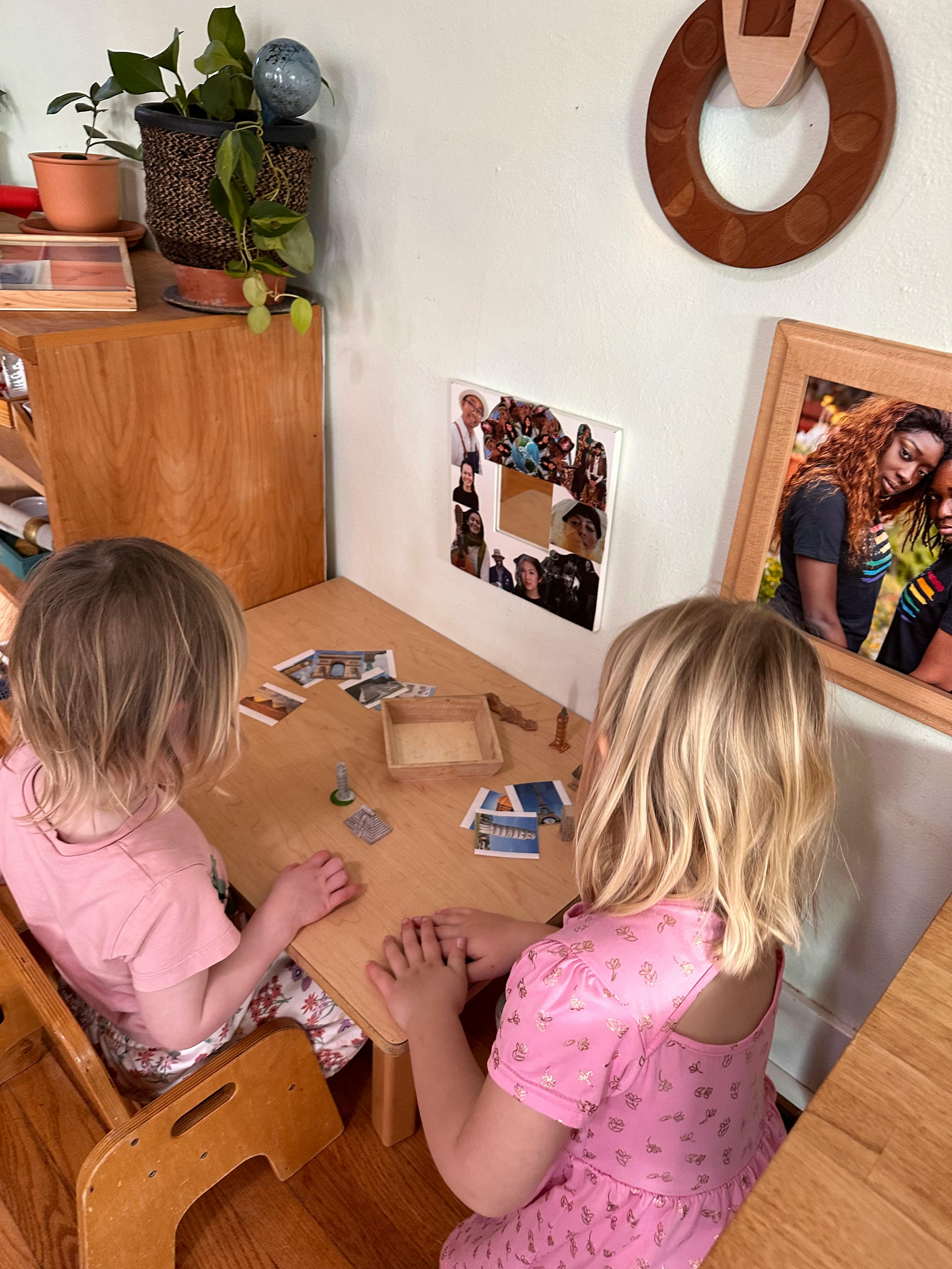 Two children sitting at a table with small objects